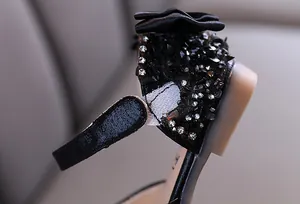 Close-up view of rhinestone and satin flower details on black girl's princess shoe
