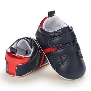Close-up detail of navy blue faux leather baby boy walking shoes with red stripes and Velcro