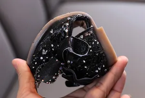 Close-up of flexible black girls' princess shoes with sparkling rhinestones and ruffles