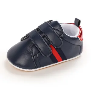 Detail shot of navy blue baby walking shoes featuring a red stripe and dual velcro straps