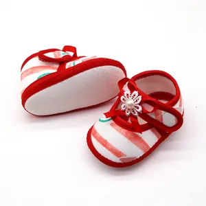 Detail van zachte baby sandalen met rode strepen en decoratie van een bloemenlint