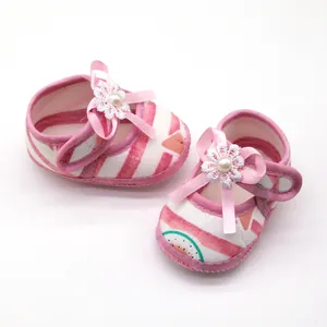 Detail van roze gestreepte babyschoenen met bloemenstrik en parel
