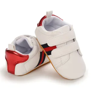 Detailed macro view of white baby sneakers featuring red and navy blue striped accents