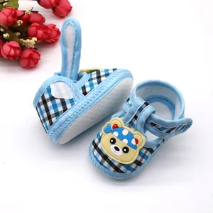 Detail van blauwe geblokte babysandalen met berendecoratie en een zachte zool