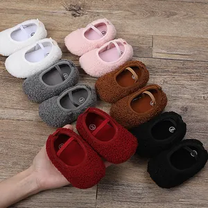 Primo piano di scarpe di peluche per neonati in vari colori su superficie in legno rustico.