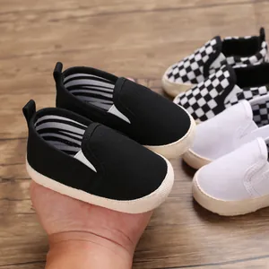 Close-up of black canvas baby slip-on shoes held in hand with multiple color variants