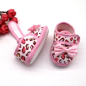 Detail van roze babyschoentjes met luipaardprint, zachte zool en strikdecoratie