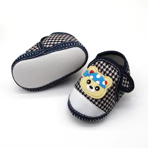 Detail van houndstooth babyschoenen met zachte antislipzolen en cartoonbeer detail.