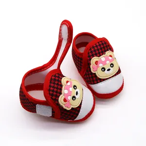 Detailweergave van rode baby sandalen met pied-de-poule patroon en beer patch