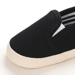 Close-up detail of black canvas baby slip-on shoe with soft sole and striped lining