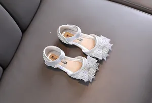 Close-up of silver sparkly princess shoes for girls with pearl bow and rhinestones.