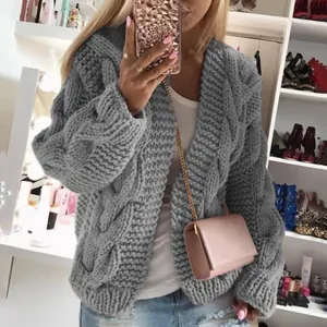 Detailoverzicht van het grijze kabelgebreide vest met een roze kettingtasje set.