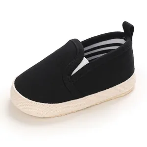 Detailed view of black canvas baby slip-on shoe featuring a soft textured beige sole