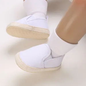Detailed view of white canvas baby shoes with comfortable non-slip soft rubber soles.