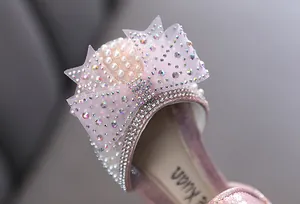 Close-up of girl's pink princess shoe featuring a sparkling rhinestone and pearl bow detail