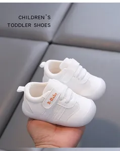 Detailed view of white toddler shoes featuring soft soles and adjustable velcro straps.
