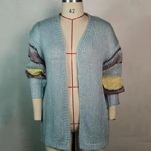 Detail van een lichtblauwe mohair cardigan met kleurrijke gestreepte mouwen.