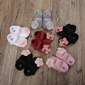 Zapatos de paseo para bebé niña con flores en varios colores sobre suelo madera