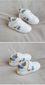 Detailed view of white toddler sneakers with blue and yellow accents and velcro straps.