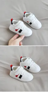 Close-up detail of white leather toddler shoes with red and black stripe accents