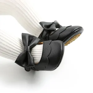 Close-up detail of black PU leather baby Mary Jane shoes with large bow and scalloped edge