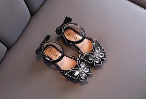 Macro view of sparkly rhinestone butterfly decoration on black girl's princess sandal