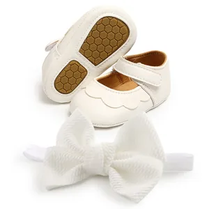 Detail view of white PU leather baby shoes with a matching textured bow headband set
