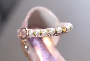 Detailaufnahme von rosa glitzernden Prinzessinnenschuhen mit Perlenriemen