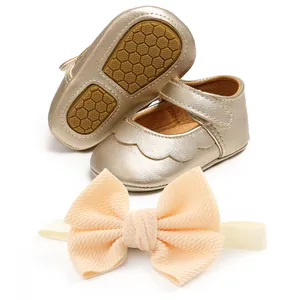 Close-up of sparkling gold baby soft sole princess shoes and matching bow headband