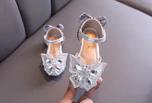Close-up of silver girls princess shoes featuring a large rhinestone butterfly decoration.