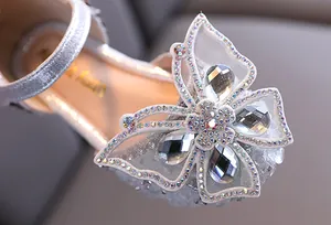 Detailed view of sparkly rhinestone butterfly decoration on girls' silver princess sandals.