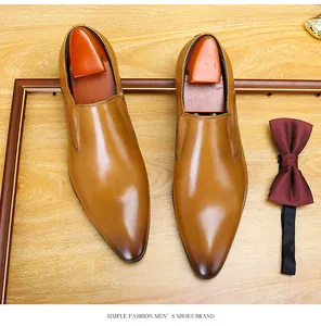 Top view of elegant tan leather slip-on loafers with wooden shoe trees and bow tie
