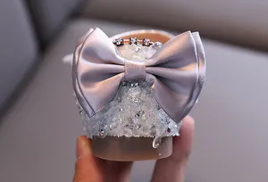 Detail of girl's princess shoe with large satin bow and iridescent rhinestones