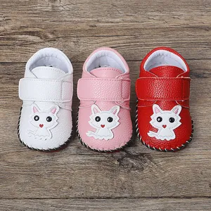 Detailansicht von Cartoon-Babyschuhen in drei Farben auf einem Holzhintergrund.