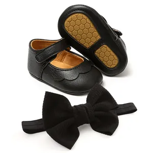 Detailed view of black PU baby walker shoes with scalloped edges and matching bow headband