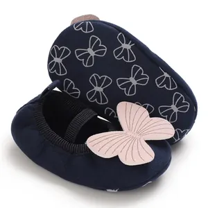 Close-up of navy blue baby walker shoes with pink butterfly applique and soft sole.