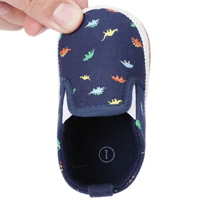 Macro view of navy blue toddler slip-on shoes featuring vibrant dinosaur prints