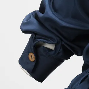 Macro detail shot of a navy blue jumpsuit sleeve cuff with a natural wooden button