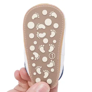 Close-up of a brown rubber baby shoe sole featuring a white anti-slip footprint and dot pattern