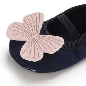 Macro detail of navy suede baby walker shoe with a decorative pink butterfly bow.