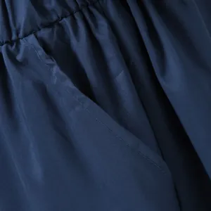 Close-up detail of navy blue jumpsuit showing elastic waistband and side pocket stitching