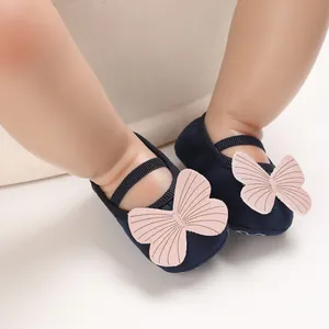 Close-up detail of navy blue baby girl walking shoes featuring a soft pink butterfly bow