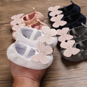 Close-up of soft-sole baby girl walking shoes with large pink butterfly decoration.