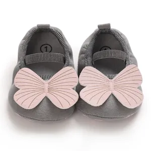 Detail of baby girl walking shoes with soft soles and pink butterfly decoration.