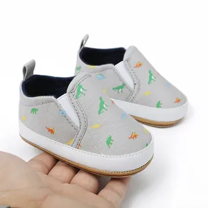 Detailweergave van grijze baby-instapschoenen met kleurrijke dinosaurusprint en witte zool