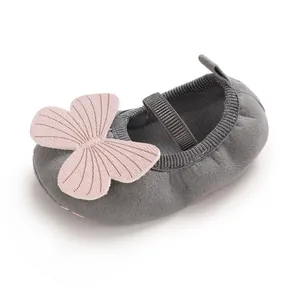 Close-up of baby girl walking shoe with pink butterfly decoration and grey fabric