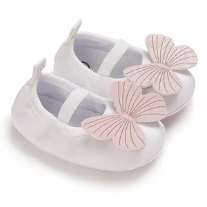 Close-up of white baby girl shoes with soft pink butterfly decorative elements