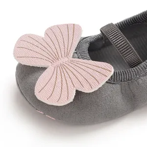 Close-up detail of soft pink butterfly applique on grey baby girl walker shoe toe