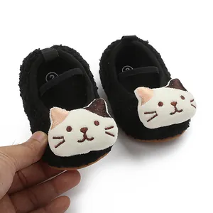 Close-up detail of black fuzzy baby walking shoes featuring a cute white cartoon cat design