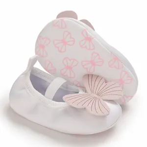 Close-up view of white baby girl infant walking shoes with pink 3D butterfly decor.